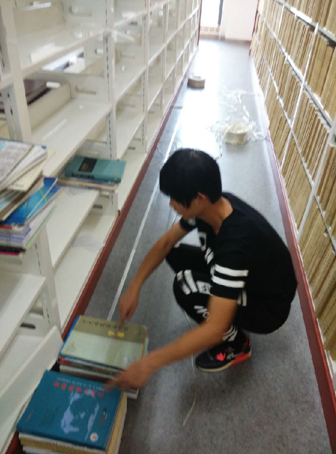 志愿者丁浩在对书架上的书籍进行整理.jpg